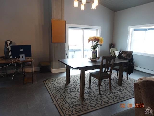 dining room featuring a notable chandelier, vaulted ceiling, and a baseboard heating unit