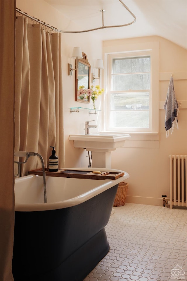 interior space with radiator heating unit, a soaking tub, and baseboards