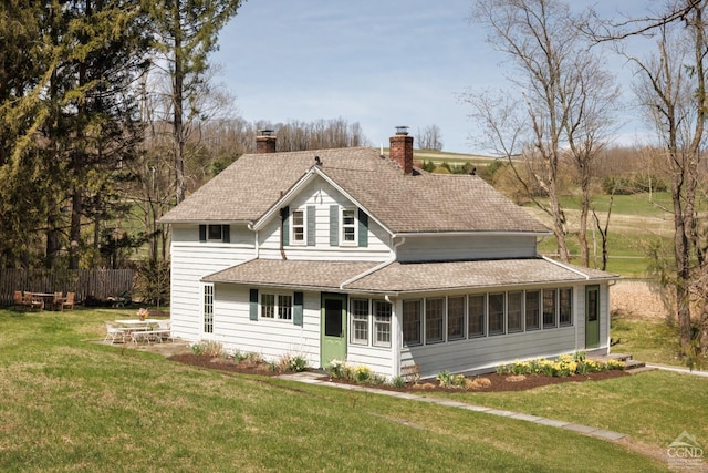 back of property featuring a lawn, fence, a sunroom, and a chimney