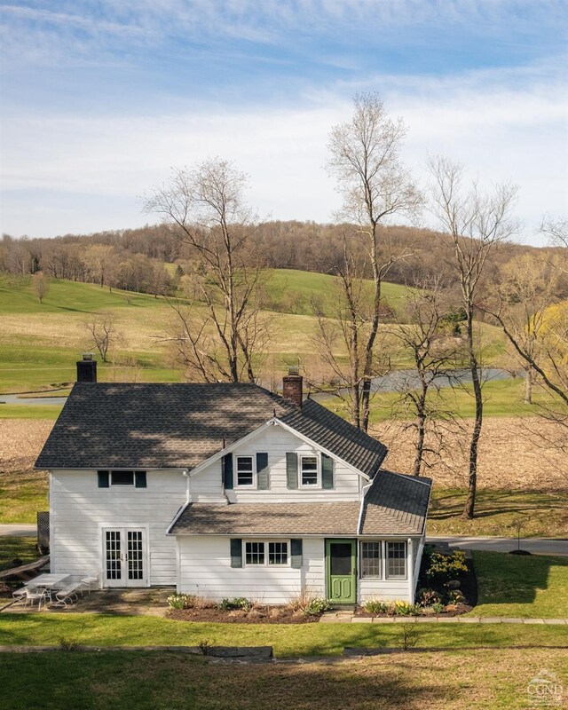 view of front facade with a chimney, french doors, and a front lawn