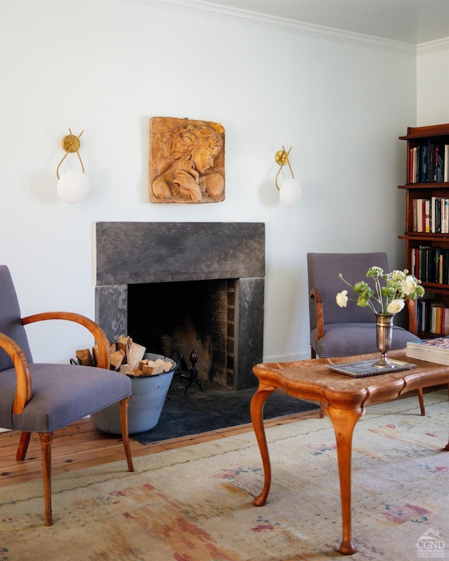 sitting room featuring wood finished floors, a fireplace, and crown molding