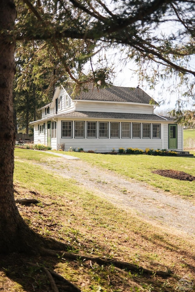 rear view of house with a shingled roof and a yard