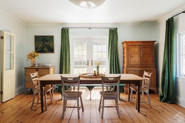 dining room featuring baseboards, ornamental molding, french doors, and light wood-style flooring