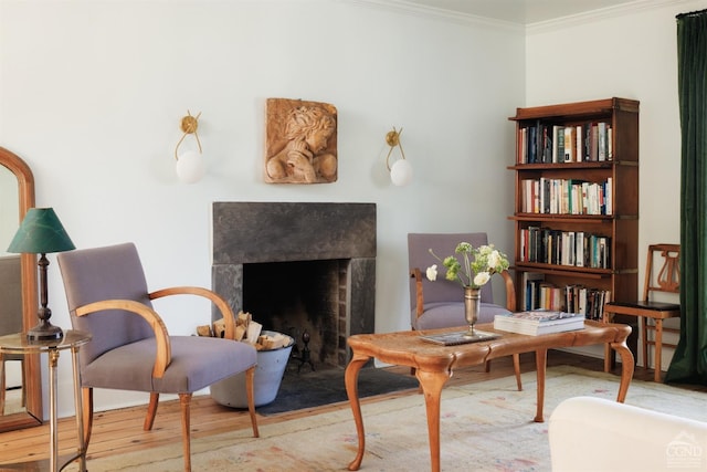 living area with ornamental molding, wood finished floors, and a fireplace