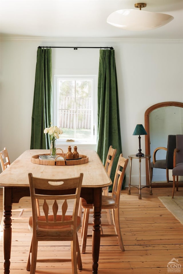 dining area with ornamental molding and light wood-style flooring