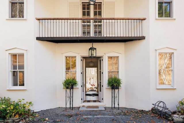 entrance to property with stucco siding and a balcony