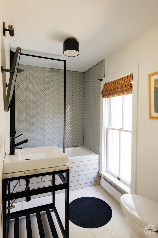 bathroom featuring tile patterned floors, a baseboard radiator, toilet, and tiled tub