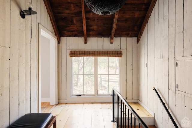 misc room with beamed ceiling, light wood-type flooring, wooden walls, and wood ceiling