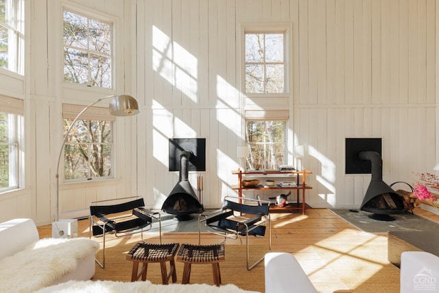 living room featuring a wood stove, wood finished floors, and a towering ceiling