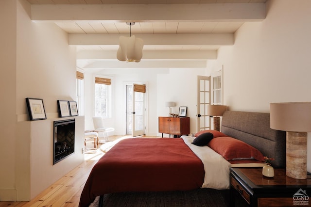 bedroom featuring beam ceiling, french doors, and light wood-type flooring