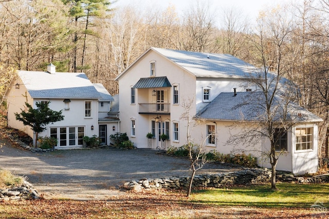 rear view of house featuring stucco siding and a balcony
