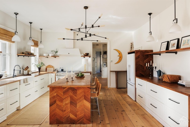 kitchen with wood counters, a sink, open shelves, and white cabinets