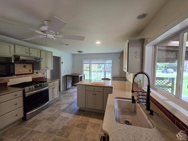 kitchen featuring decorative backsplash, ceiling fan, sink, and stainless steel stove