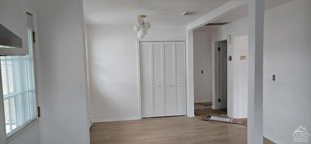 interior space with baseboards, light wood finished floors, visible vents, and a healthy amount of sunlight