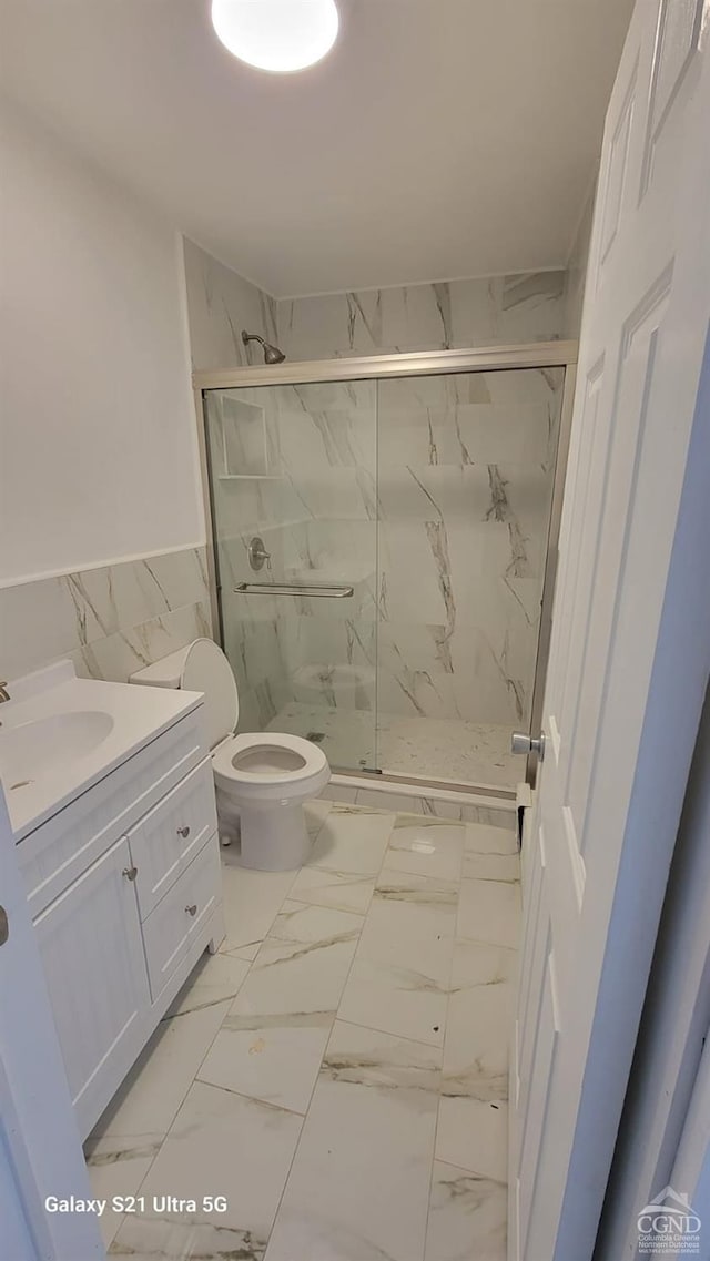 bathroom featuring toilet, marble finish floor, and a marble finish shower