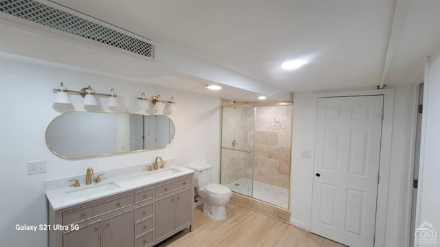 bathroom with wood finished floors, a stall shower, a sink, and visible vents