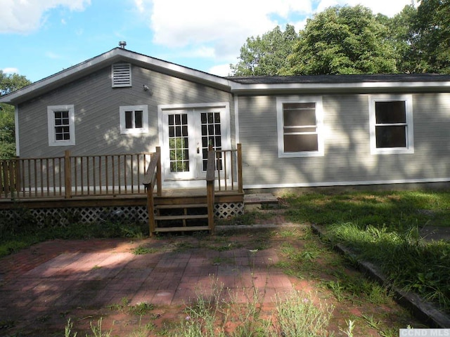 rear view of property with french doors, a wooden deck, and a patio