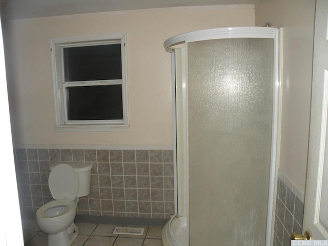 bathroom featuring tile patterned flooring, tile walls, toilet, and walk in shower