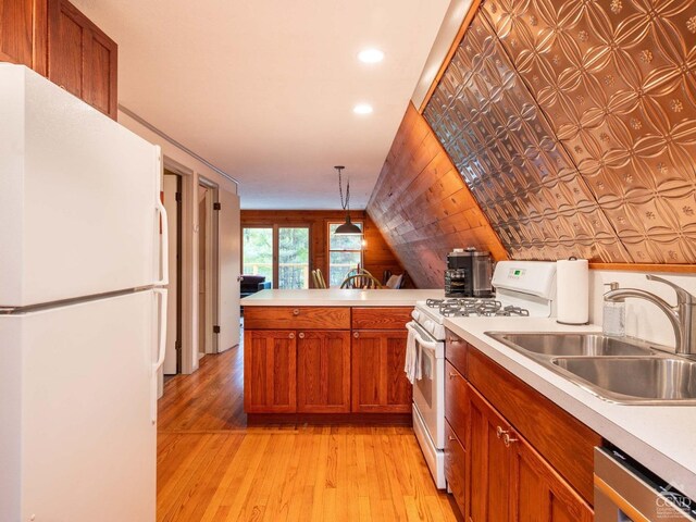 kitchen featuring sink, hanging light fixtures, light hardwood / wood-style floors, lofted ceiling, and white appliances