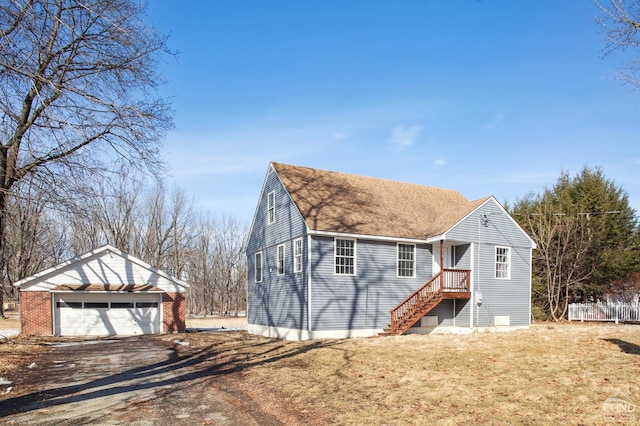 view of front of house featuring an outbuilding, a shingled roof, a front lawn, and a garage