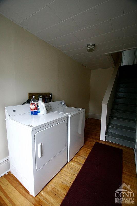 clothes washing area with washer and clothes dryer and wood-type flooring