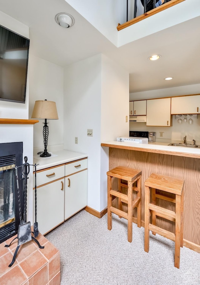 kitchen with a breakfast bar, light carpet, cream cabinets, sink, and kitchen peninsula