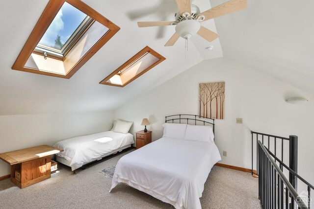 carpeted bedroom with ceiling fan and vaulted ceiling with skylight