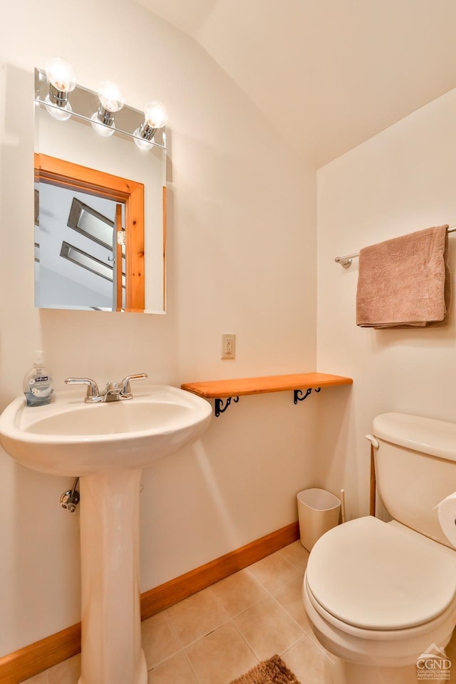 bathroom featuring toilet, tile patterned floors, lofted ceiling, and sink