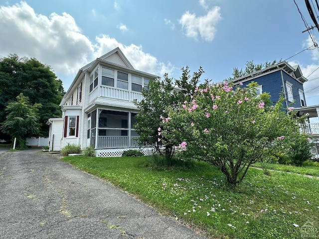 view of front of home featuring a sunroom and a front lawn