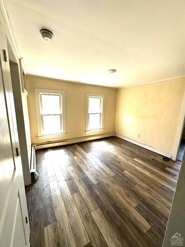 empty room with baseboard heating and dark hardwood / wood-style flooring