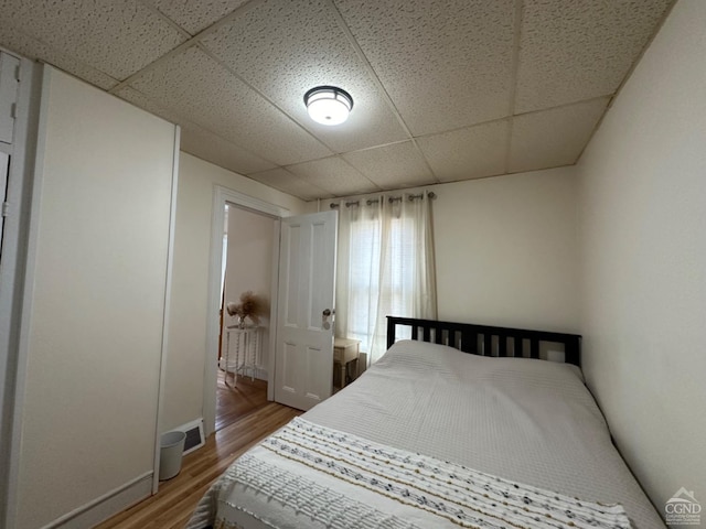 bedroom featuring hardwood / wood-style floors and a drop ceiling