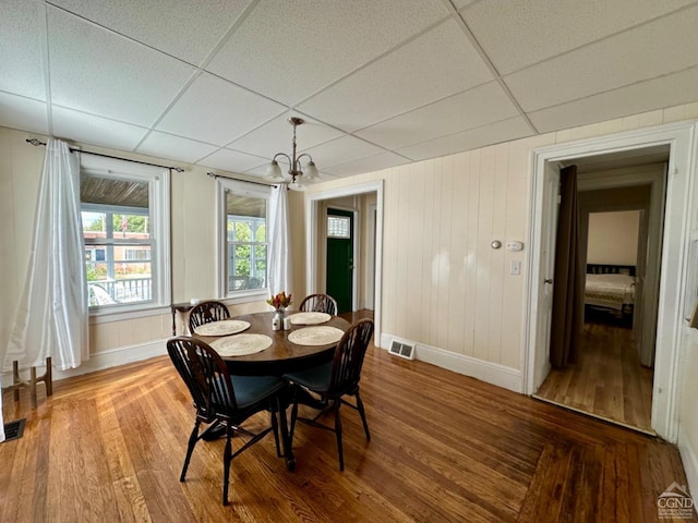 dining room featuring hardwood / wood-style flooring, a paneled ceiling, and a chandelier