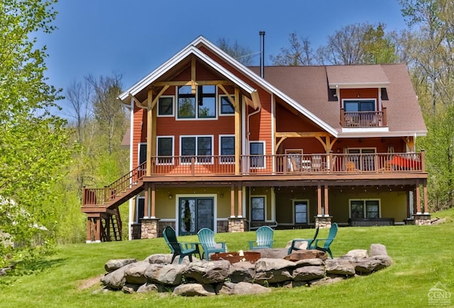 rear view of house with a yard, a deck, and a fire pit