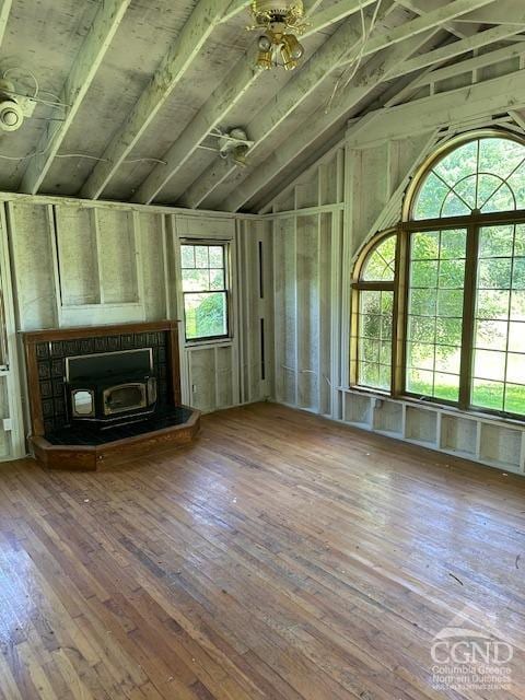 unfurnished living room with wood-type flooring, a wood stove, ceiling fan, and lofted ceiling