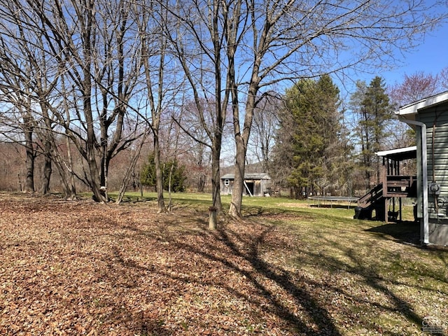 view of yard with stairs, a trampoline, an outbuilding, and a wooden deck