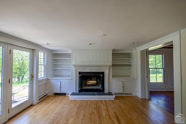 unfurnished living room with built in shelves, light hardwood / wood-style flooring, and a baseboard heating unit