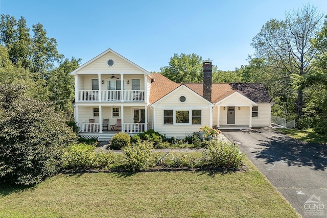 greek revival inspired property with a front yard, a porch, and a balcony