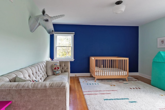 bedroom with a nursery area and hardwood / wood-style flooring