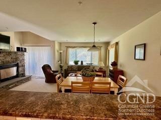 carpeted dining area with a stone fireplace