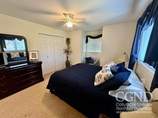 bedroom with a closet, ceiling fan, and light colored carpet