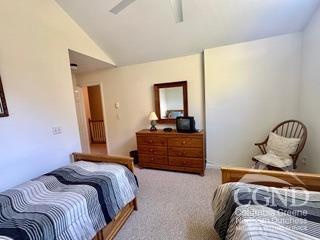 carpeted bedroom with ceiling fan and vaulted ceiling