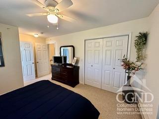 carpeted bedroom featuring ceiling fan and a closet