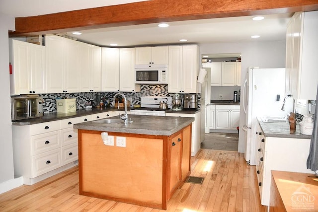 kitchen featuring sink, an island with sink, white appliances, white cabinets, and light wood-type flooring