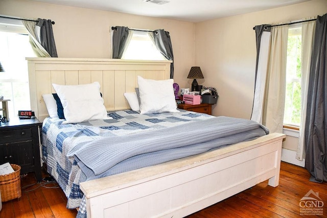 bedroom with multiple windows and dark hardwood / wood-style floors