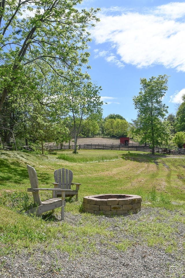 surrounding community featuring a yard, a rural view, and an outdoor fire pit