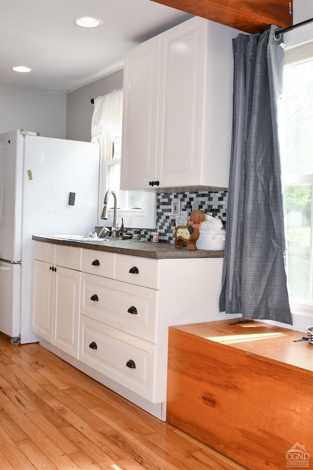 kitchen featuring white cabinetry, sink, tasteful backsplash, white refrigerator, and light wood-type flooring