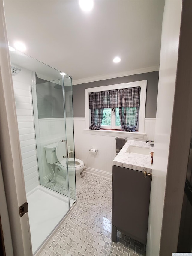 bathroom with vanity, toilet, a shower with door, and crown molding