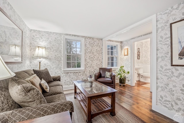 living room with wallpapered walls, hardwood / wood-style flooring, and baseboards