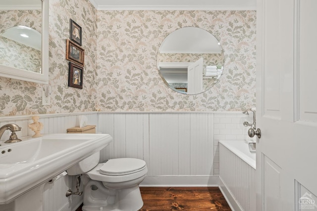 bathroom featuring wallpapered walls, toilet, wainscoting, and wood finished floors