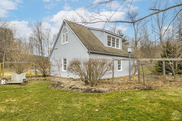 view of home's exterior with a shingled roof and a yard
